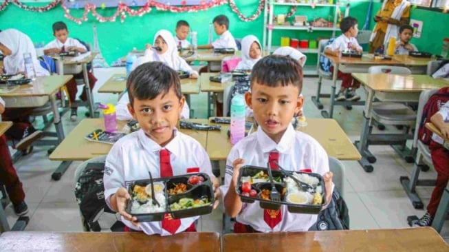 Foto: Siswa-siwi menyantap hidangan makan bergizi saat uji coba program makam bergizi gratis.